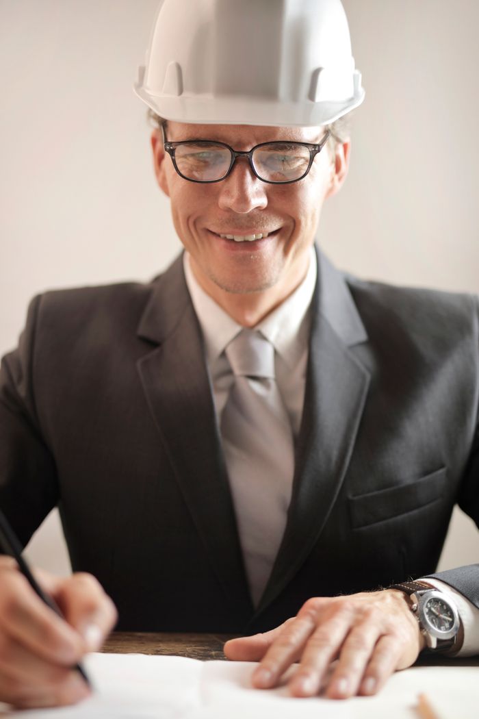 service-01 Male engineer in formal attire reviewing and signing construction documents indoors.
