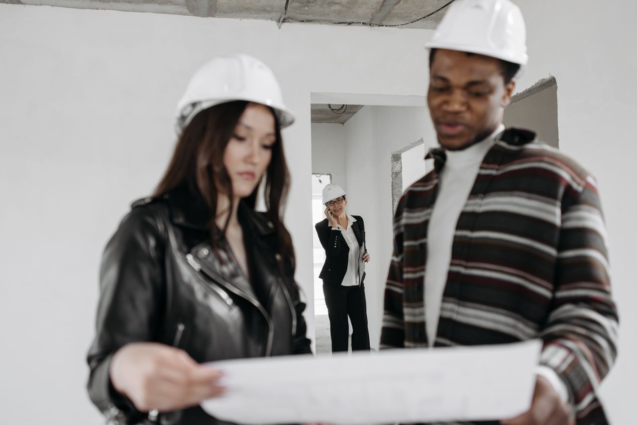 service-03 Interracial team of architects reviewing plans inside a new construction site.