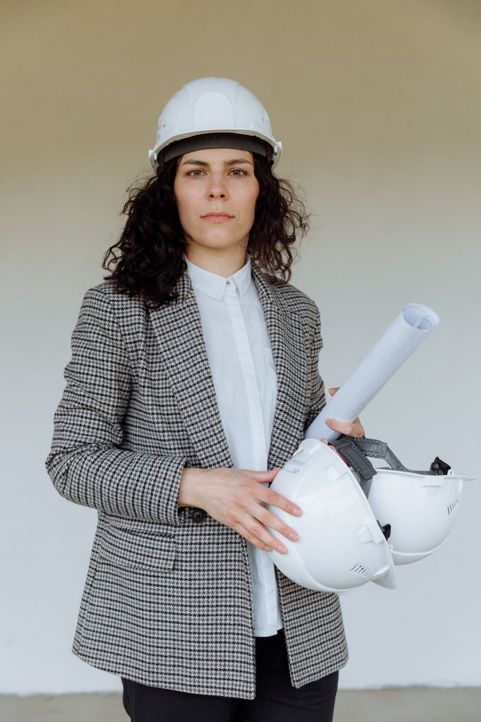 Crafting Captivating Headlines: Your awesome post title goes here Female architect in safety gear holding blueprints, showcasing professionalism.